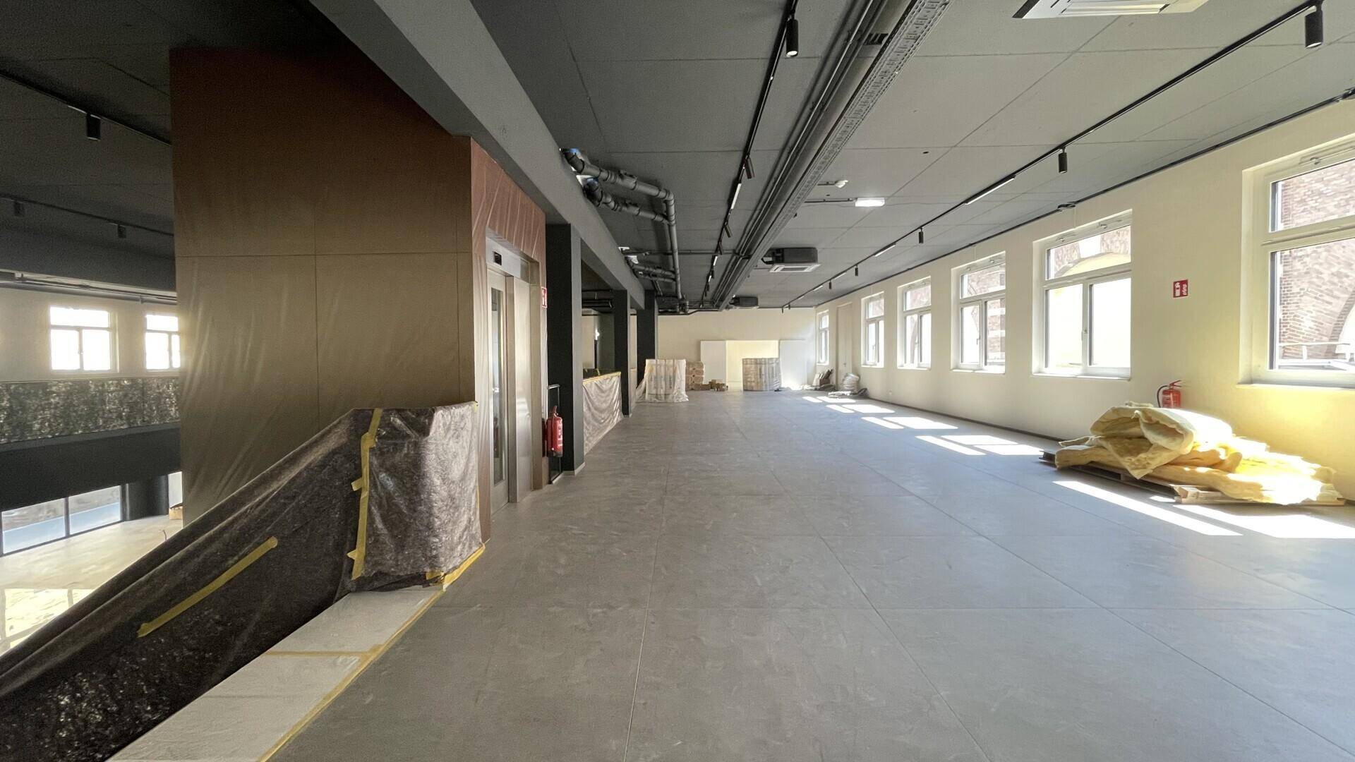 Langer Bürobereich mit Blick auf den Aufzug und die Fensterfronten.