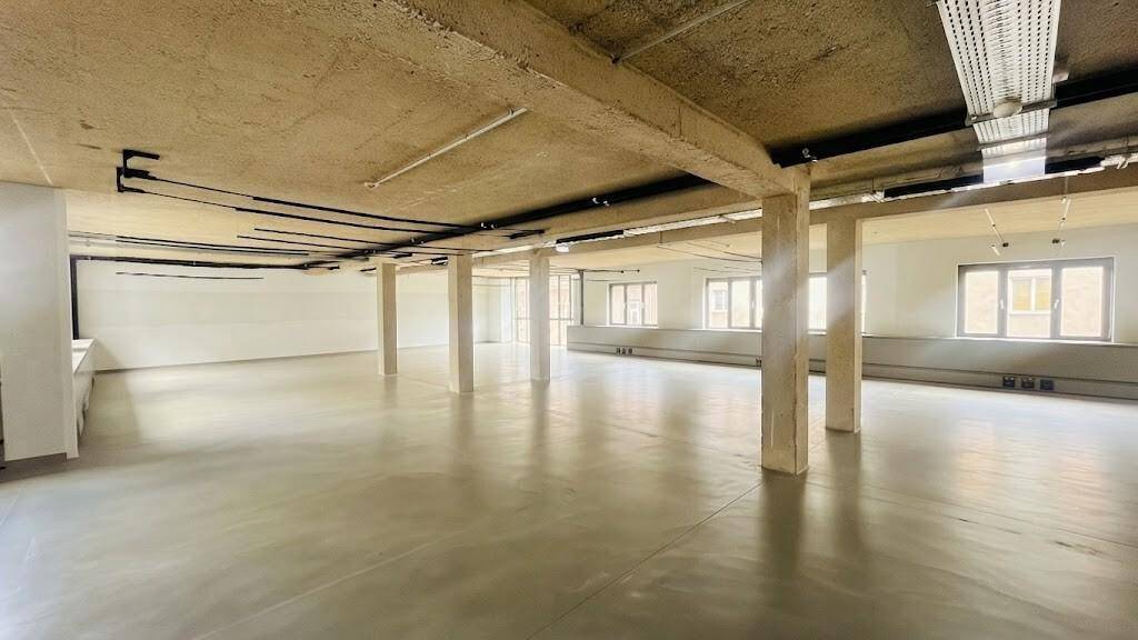 Großer, offener Gewerberaum mit Sichtbetondecke, freiliegenden Säulen und viel natürlichem Licht.