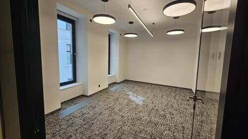 Heller Büroraum mit modernem Teppichboden, großen Fenstern und zeitgemäßer Deckenbeleuchtung.