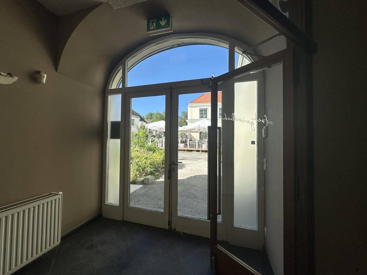 Ein heller Eingangsbereich mit großen Glastüren, die den Blick auf einen sonnigen Innenhof freigeben.