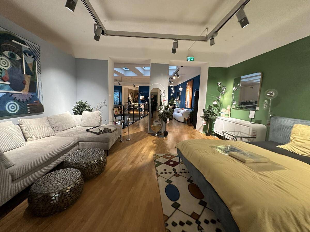 Geräumiger Verkaufsraum mit Holzboden, verschiedenen Möbeln und farbigen Wänden.