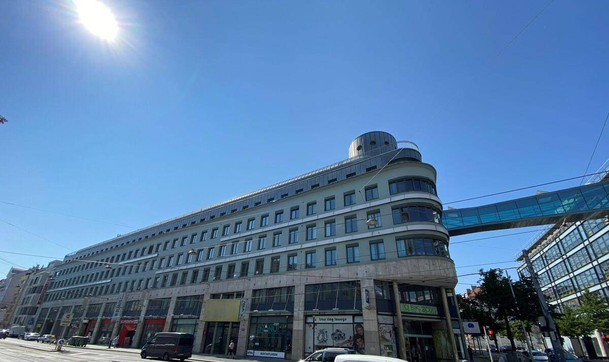 Weitläufiges modernes Geschäftsgebäude mit geschwungener Architektur und vielen Fenstern unter blauem Himmel.
