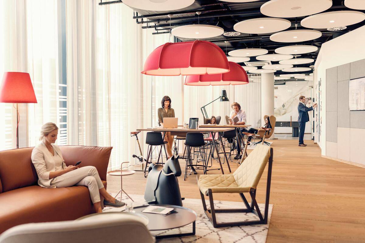 Moderner Co-Working-Bereich mit stilvollen Möbeln, großen Fenstern und einzigartigen Deckenleuchten.