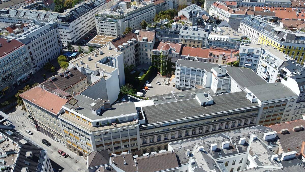 Luftaufnahme eines Stadtblocks mit verschiedenen Gebäuden, Dächern und städtischer Bebauung.
