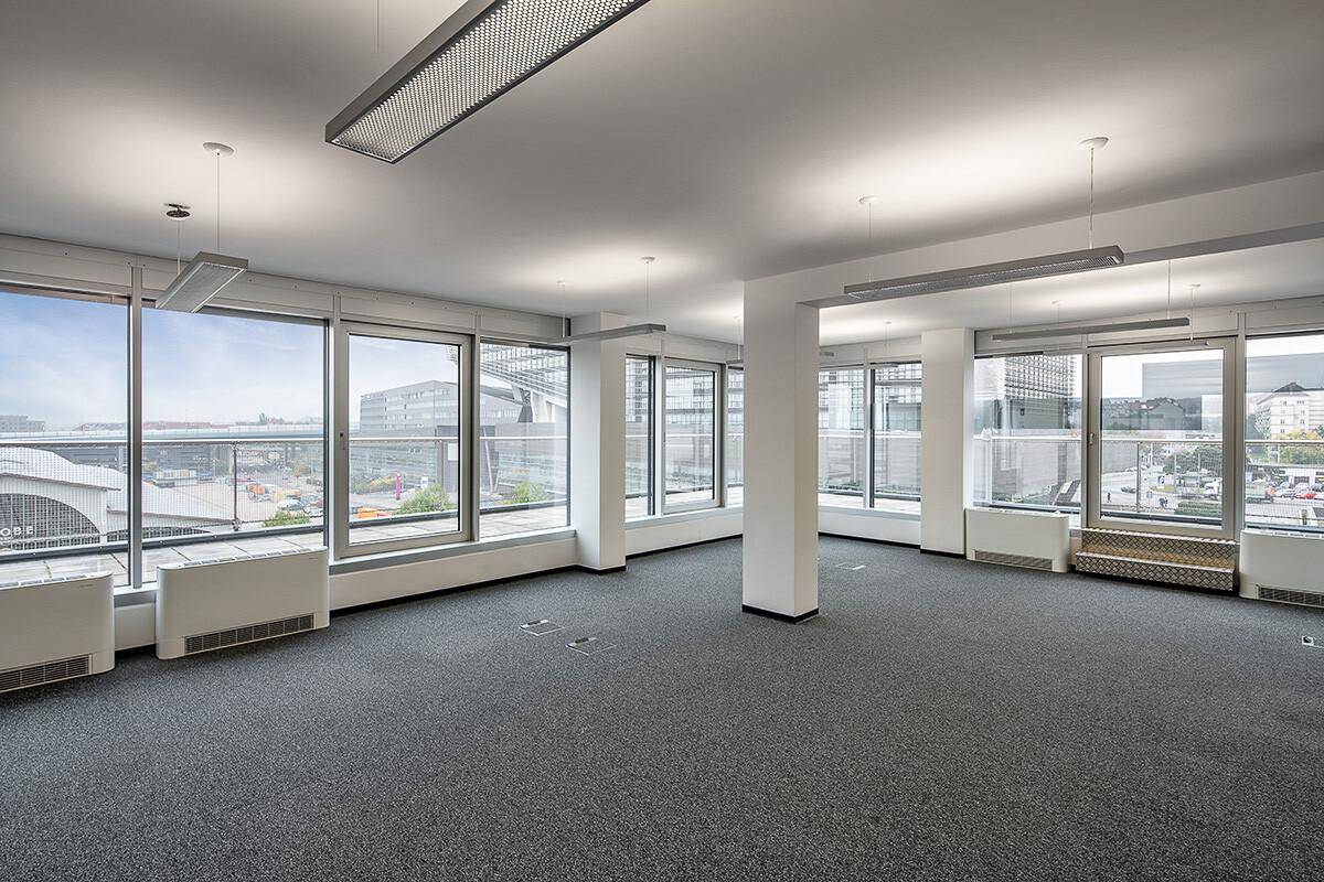 Heller Büroraum mit Teppichboden und großen Fenstern, die einen weiten Blick über die Stadtlandschaft ermöglichen.