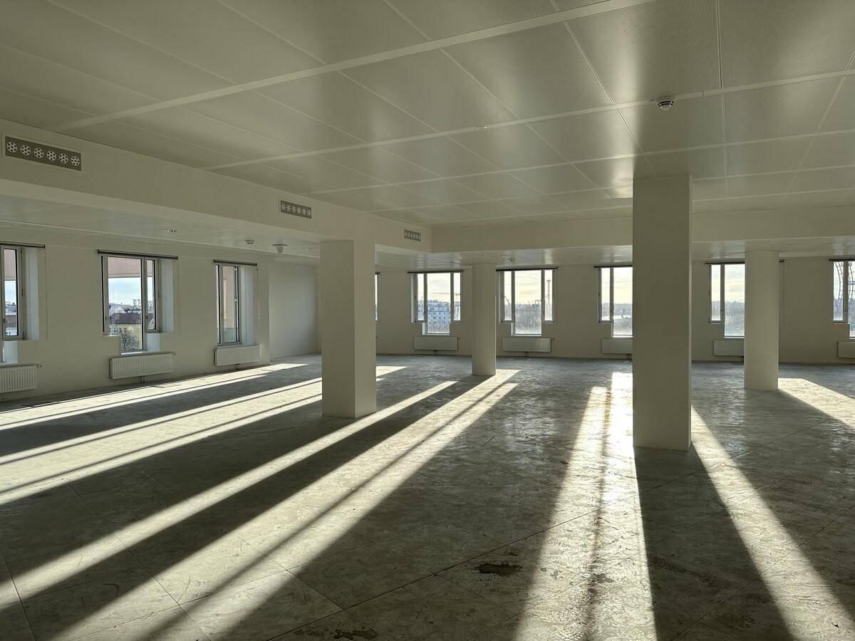 Weitläufiger Bürobereich mit Säulen, großen Fenstern und langen Schatten durch die Sonneneinstrahlung.