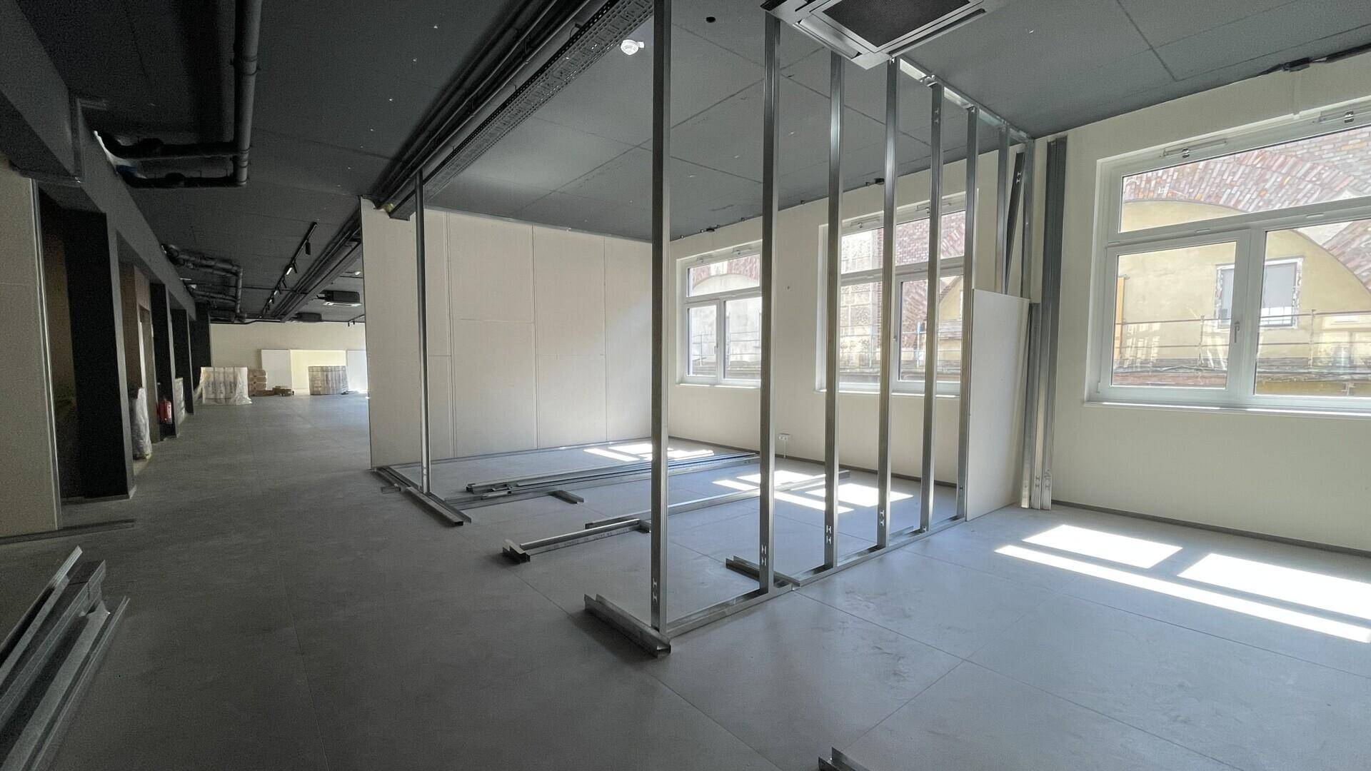 Innenansicht eines zukünftigen Bürobereichs mit Fensterfronten und Metallrahmen für Trennwände.