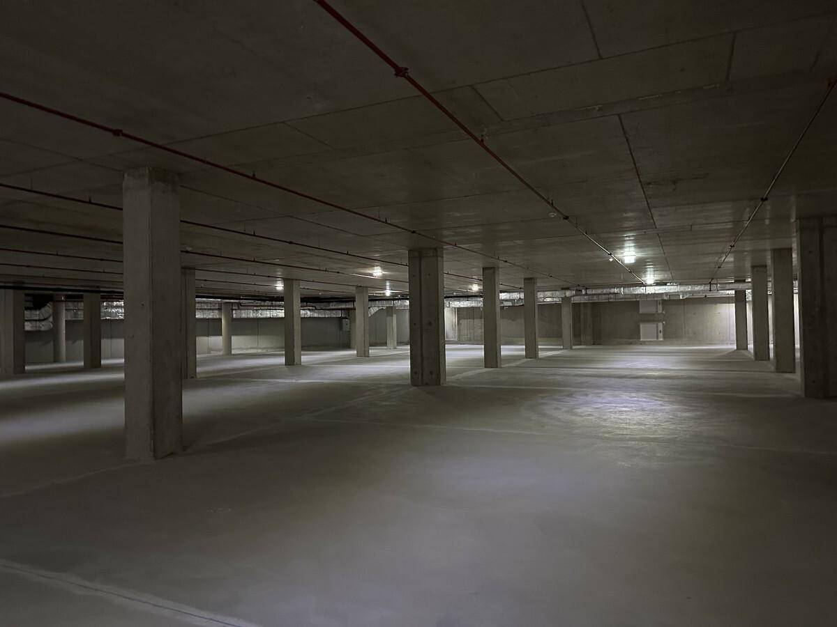 Geräumige Tiefgarage mit Betonboden und -pfeilern, bereit zur Nutzung.