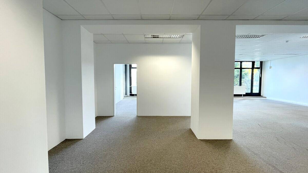 Heller, leerer Gewerberaum mit Teppichboden und weißen Wänden, bereit für die individuelle Gestaltung.