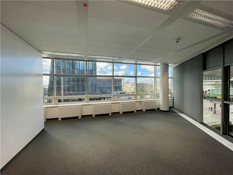 Geräumiges, unmöbliertes Büro mit Teppichboden und großen Fenstern, die viel Tageslicht und einen Blick nach draußen bieten.