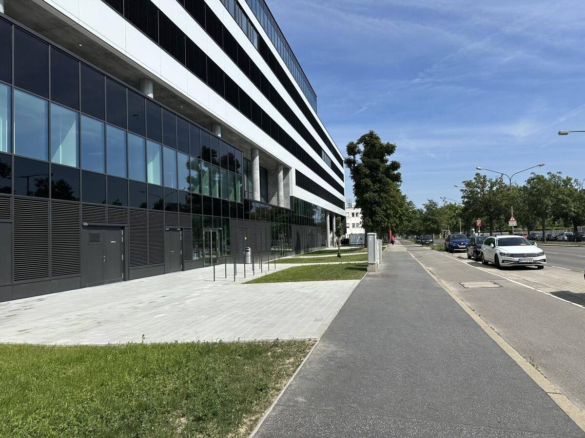 Die moderne Fassade eines Geschäftsgebäudes entlang einer Straße mit parkenden Autos.