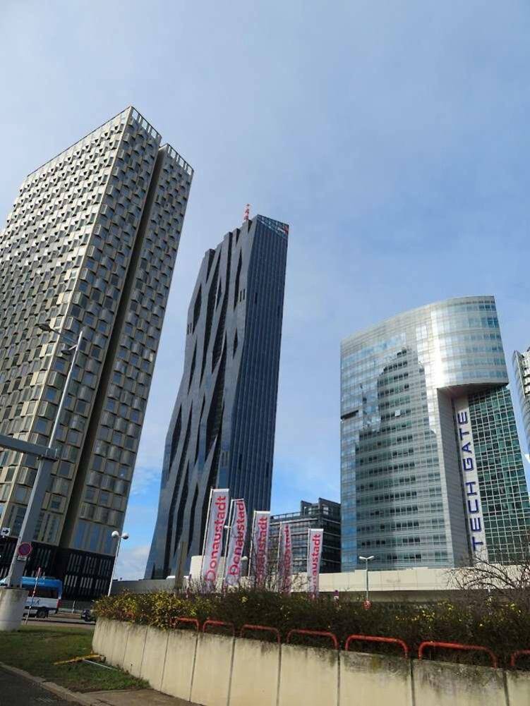 Beeindruckende Skyline mit mehreren modernen Hochhäusern und einzigartigen architektonischen Designs unter blauem Himmel.