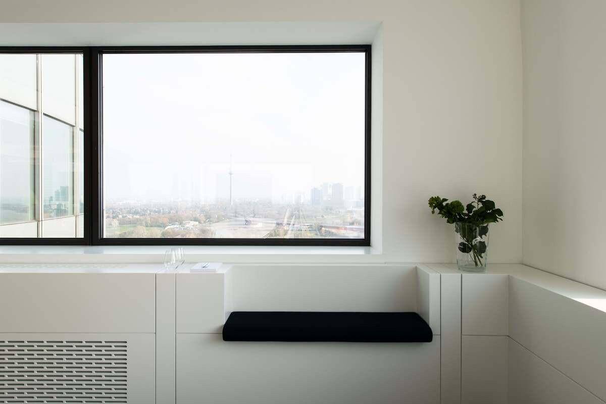 Detailansicht eines Fensters in einem Büro mit einer integrierten Sitzbank und Blick auf die Stadt.