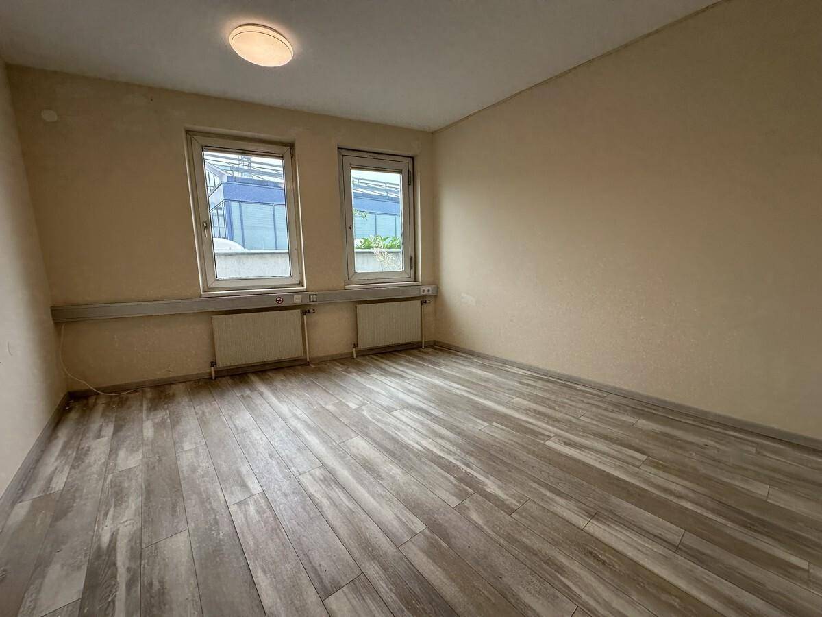 Kleineres Büro mit Laminatboden und zwei Fenstern, die für ausreichend Tageslicht sorgen.