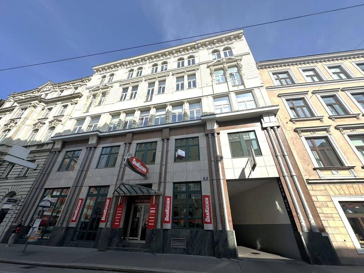 Mehrstöckiges Gebäude mit Geschäftsflächen im Erdgeschoss und Wohn- oder Büroeinheiten darüber, mit Durchfahrt.
