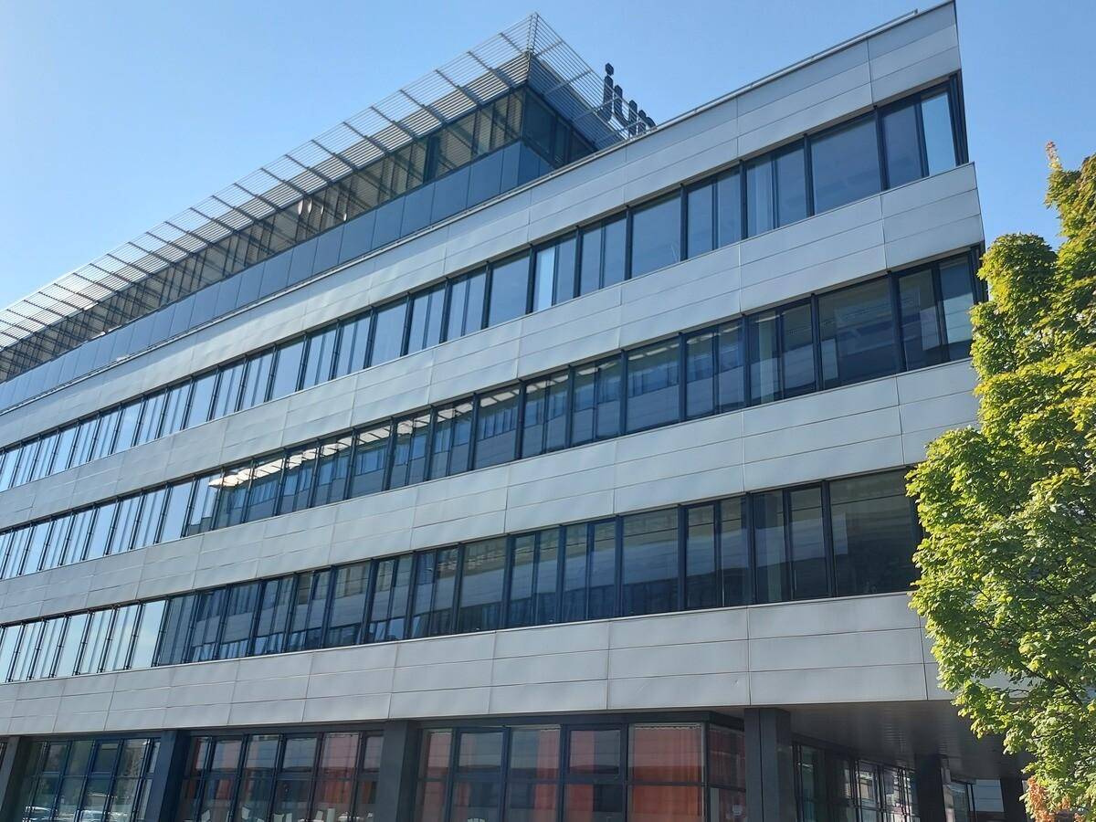 Detailansicht der modernen Bürogebäude-Fassade mit vielen Fenstern und dem Firmenlogo unter klarem Himmel.