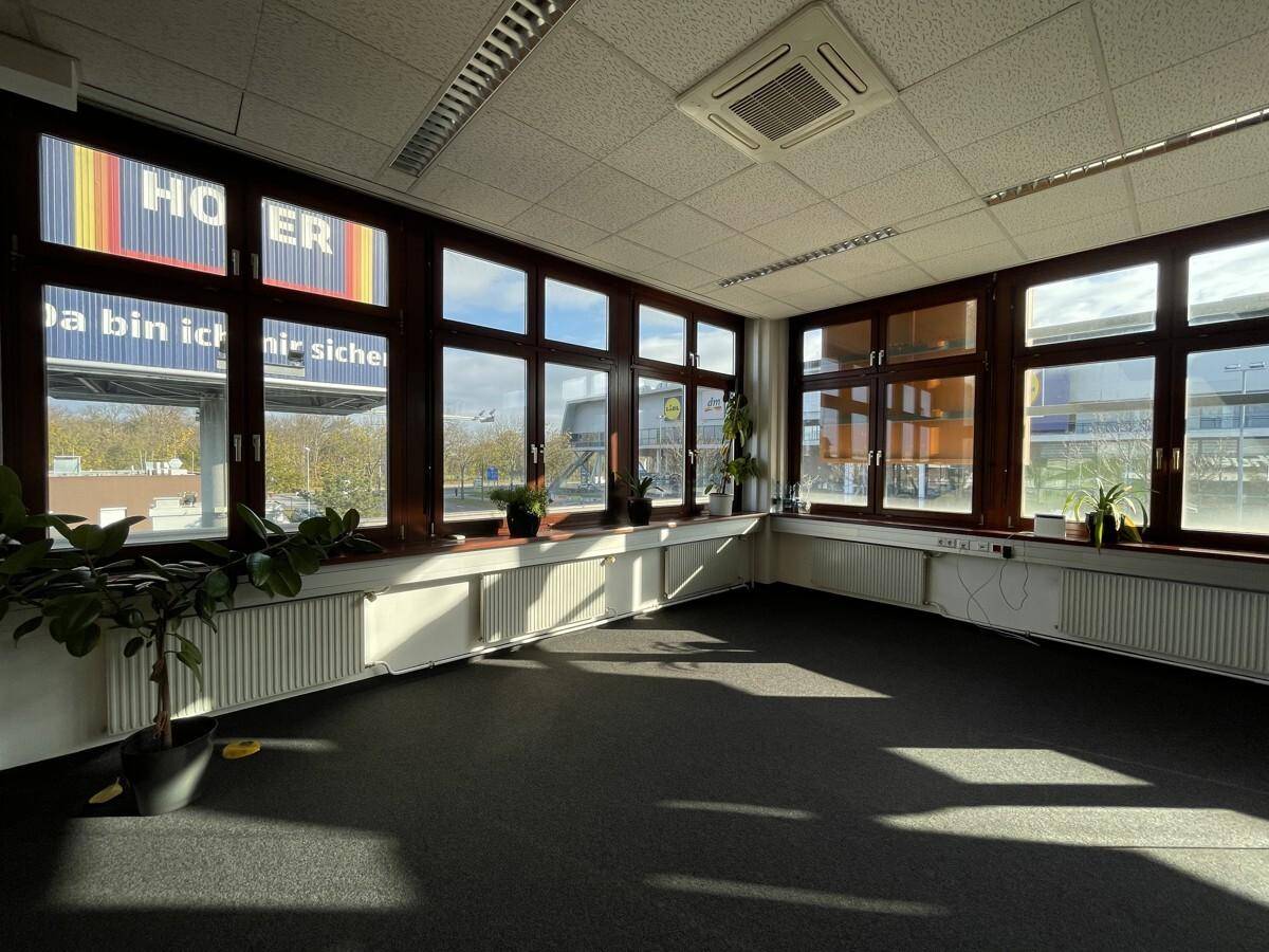 Büro mit großen Fenstern, die viel Tageslicht hereinlassen und einen weiten Blick auf die Umgebung bieten.
