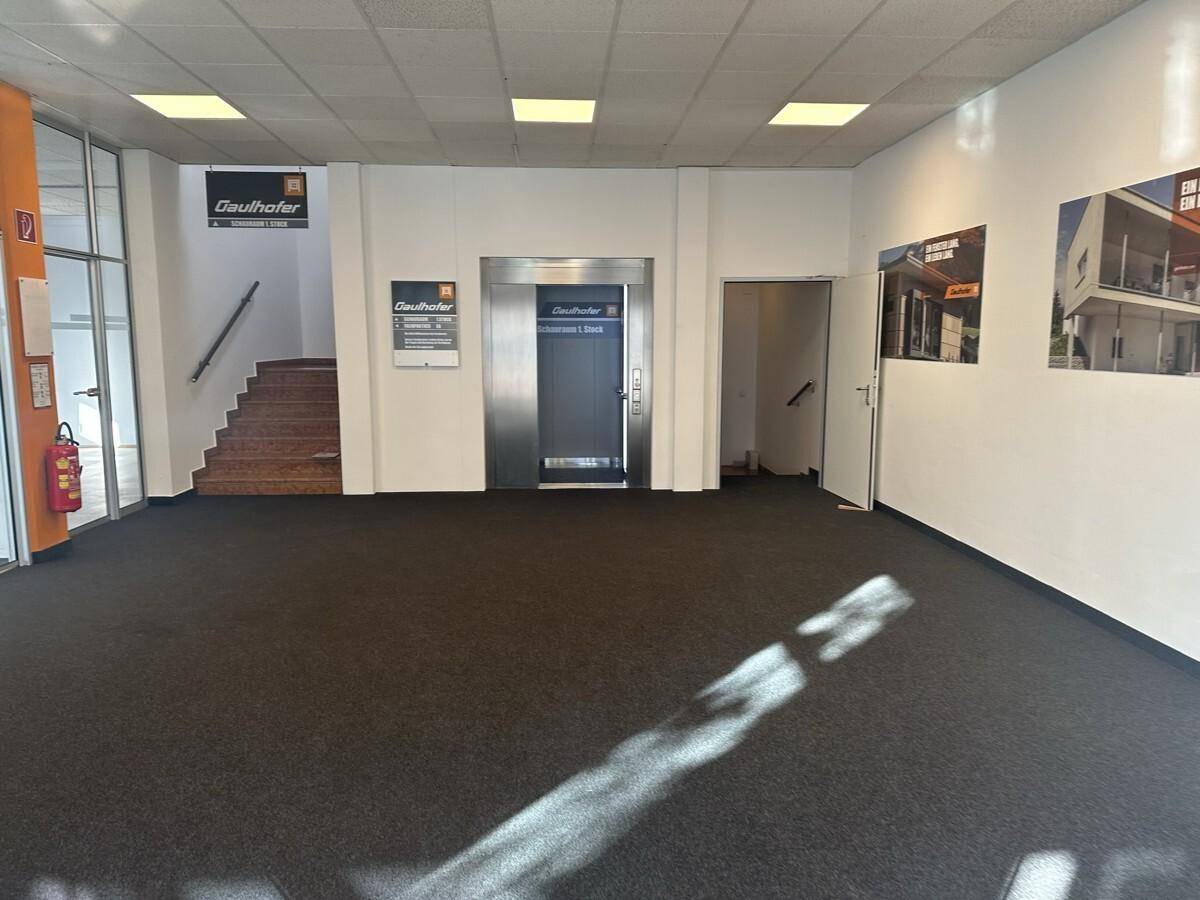 Geräumiger Eingangsbereich mit Teppichboden, Treppe und einem modernen Aufzug für bequemen Zugang zu den Etagen.