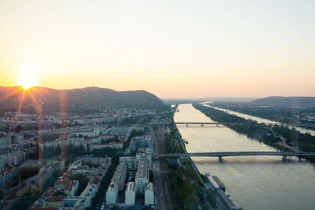 Panoramablick bei Sonnenuntergang über die Donau, die Stadt und die umliegenden Berge.