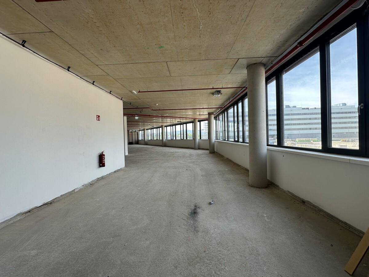 Langer, offener Gewerberaum mit einer durchgehenden Fensterfront, die eine weite Aussicht ermöglicht.