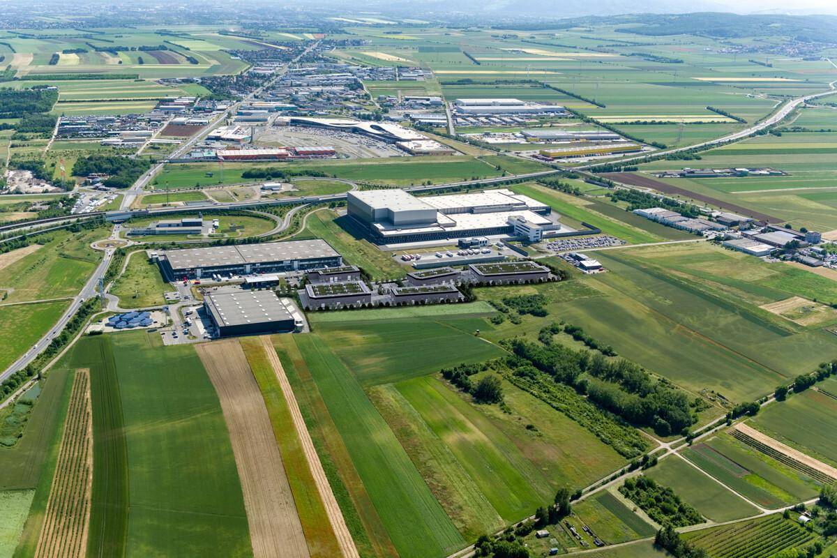 Weitläufige Luftaufnahme eines Gewerbegebiets eingebettet in ländliche Landschaft mit Autobahnanbindung.