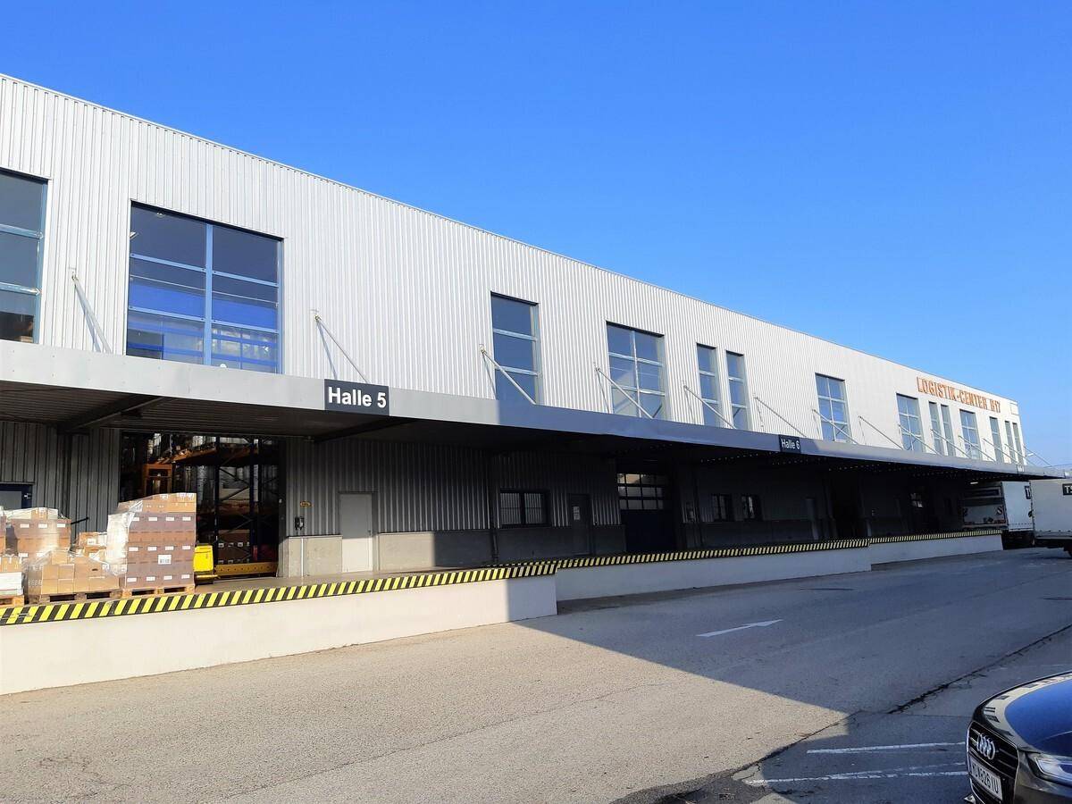 Langes Logistikzentrum mit mehreren Ladebereichen, großen Fenstern und einem geparkten LKW.