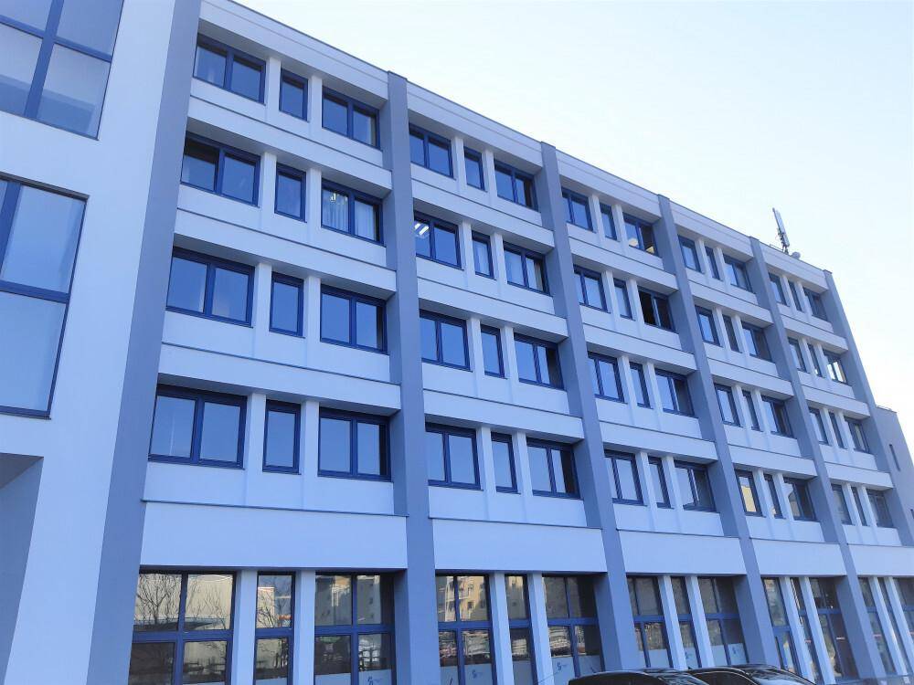 Ansicht eines modernen Bürogebäudes mit vielen blauen Fenstern und einer hellen Fassade.