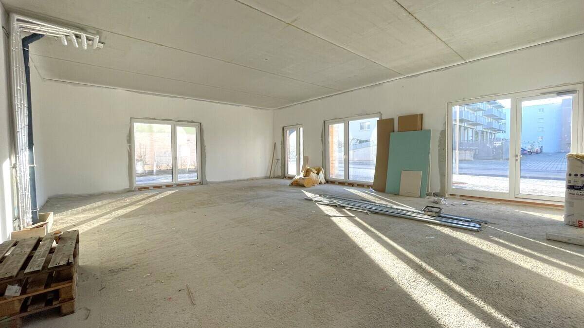 Heller und weitläufiger Rohbau-Raum mit mehreren Fenstern, bereit für den Innenausbau.