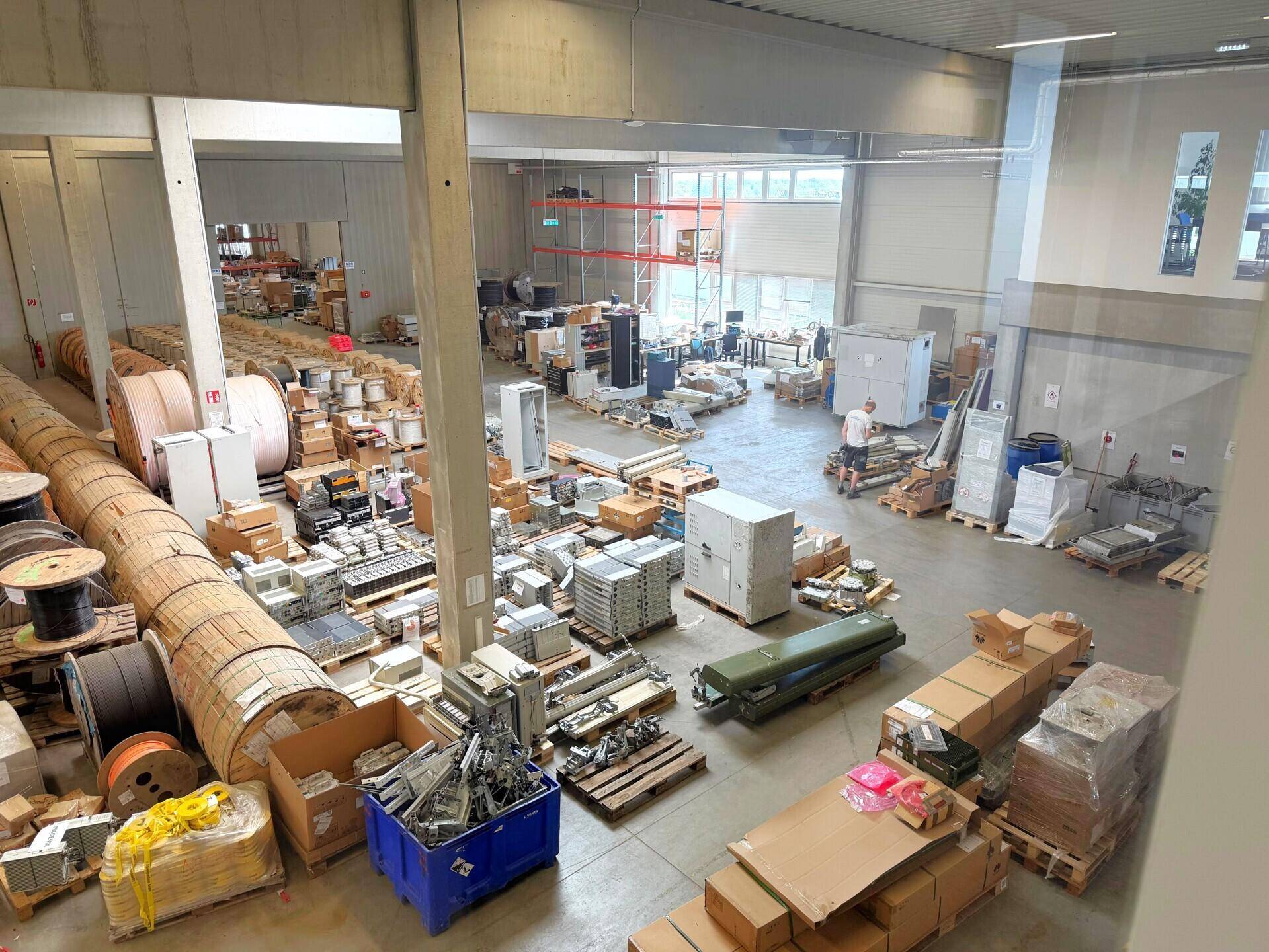 Weitläufige Lagerfläche mit verschiedenen Materialien, Kisten und Geräten auf dem Betonboden.