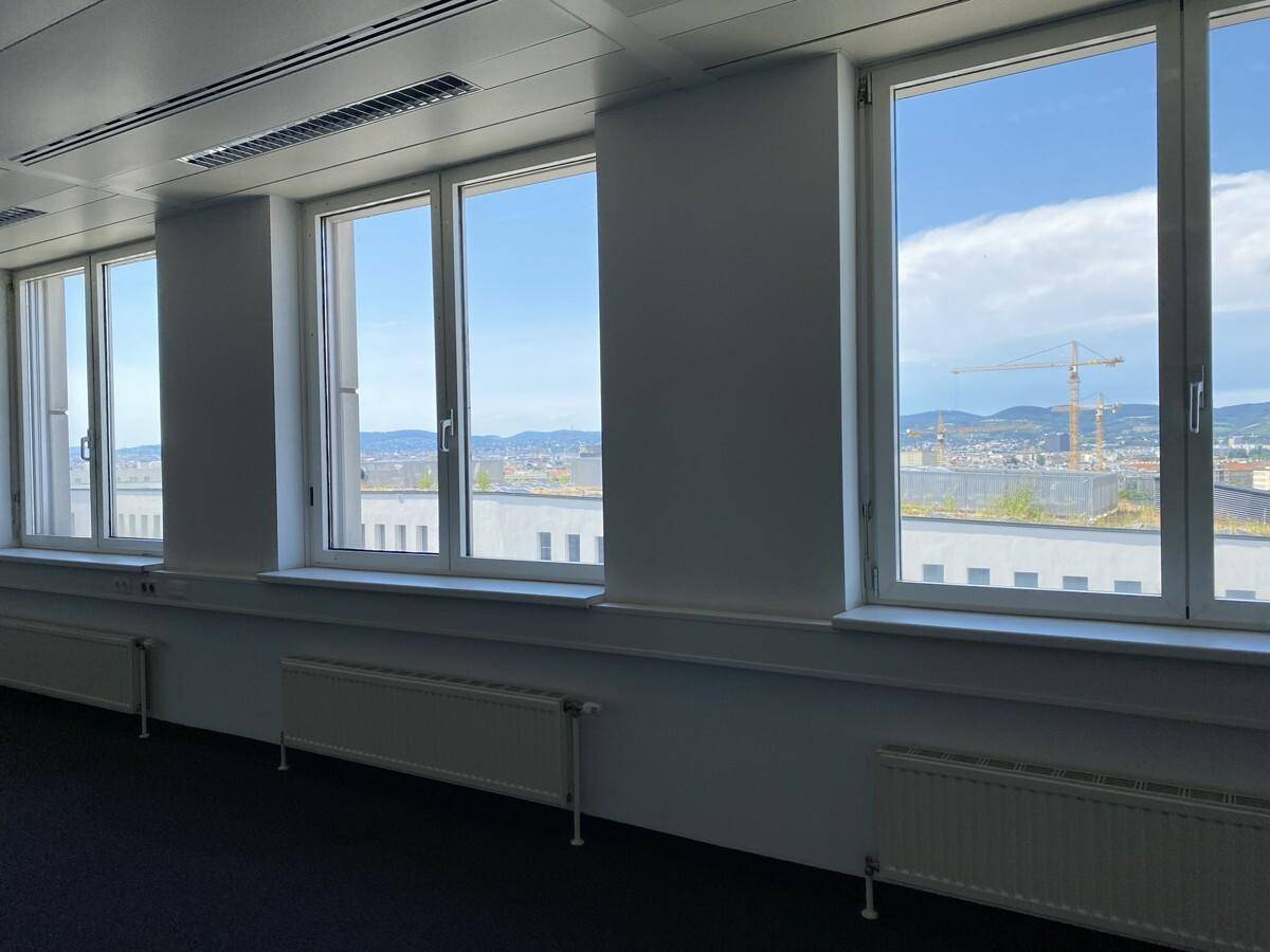Büroraum mit weitem Blick über die Stadt und Baustellen durch große Fenster.