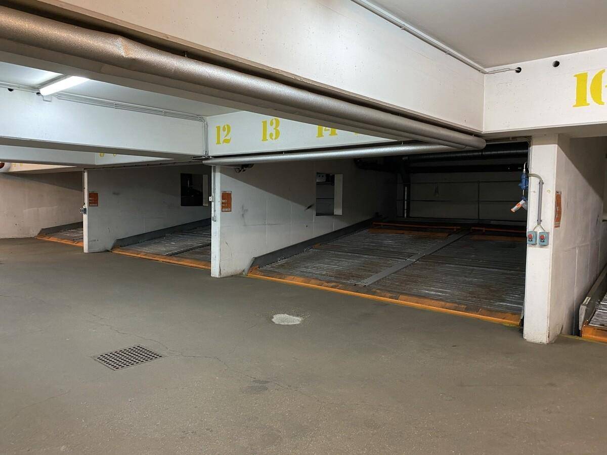 Tiefgarage mit nummerierten Stellplätzen und mechanischen Parksystemen für Fahrzeuge.