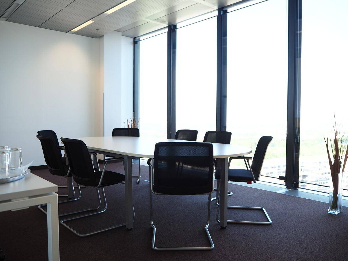 Heller Konferenzraum mit großem Tisch, bequemen Stühlen und raumhohen Fenstern mit Weitblick.