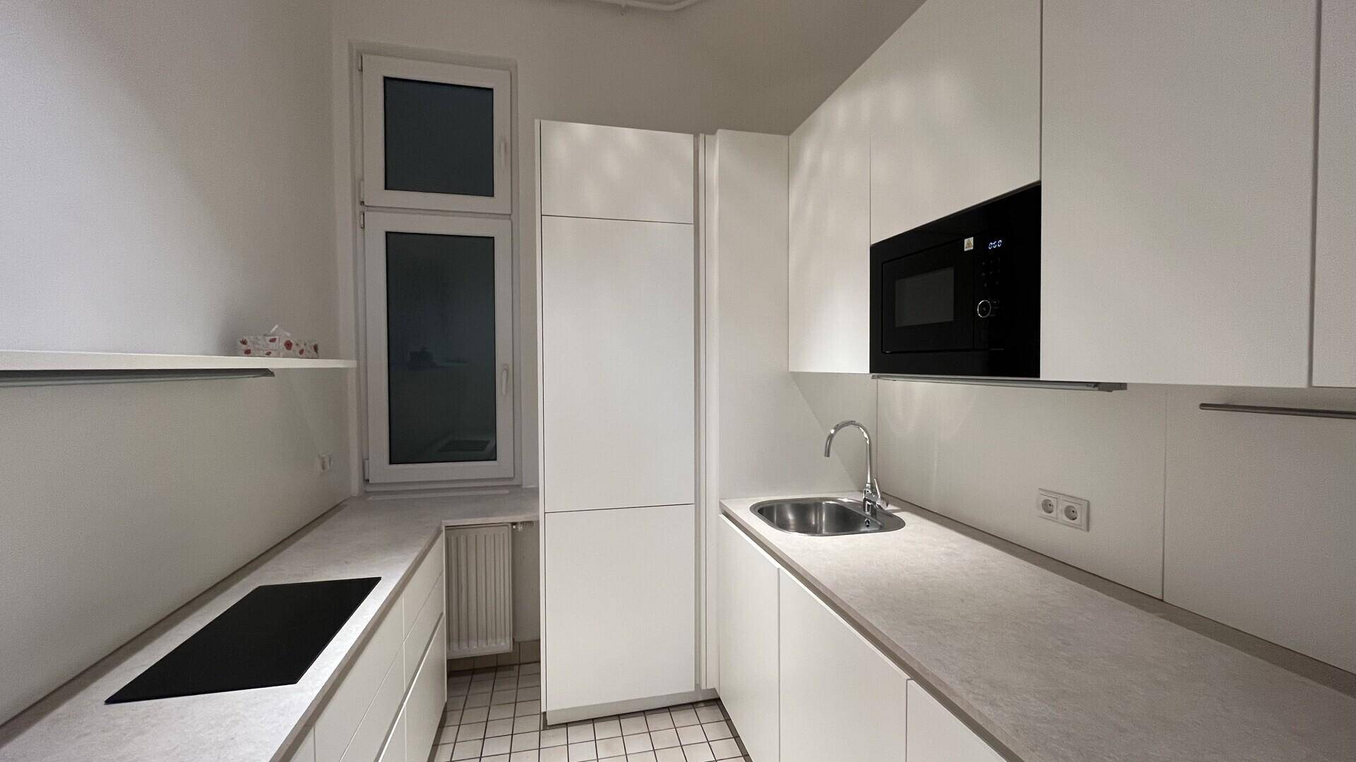 Moderne Einbauküche mit weißen Schränken, Induktionskochfeld und integrierter Mikrowelle, sehr gepflegt.