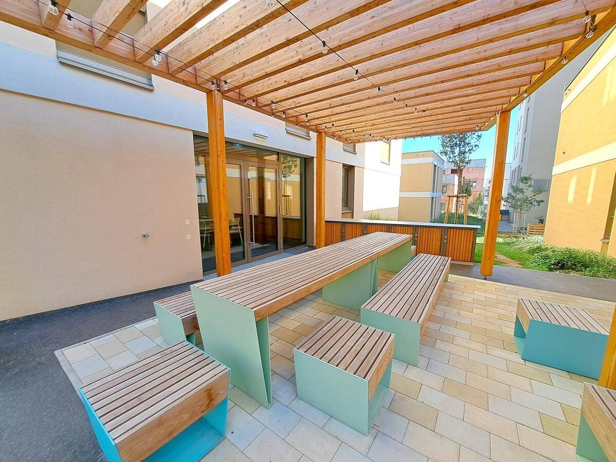 Gemütlicher Außenbereich mit Pergola, großem Holztisch und Bänken, ideal für gesellige Stunden.