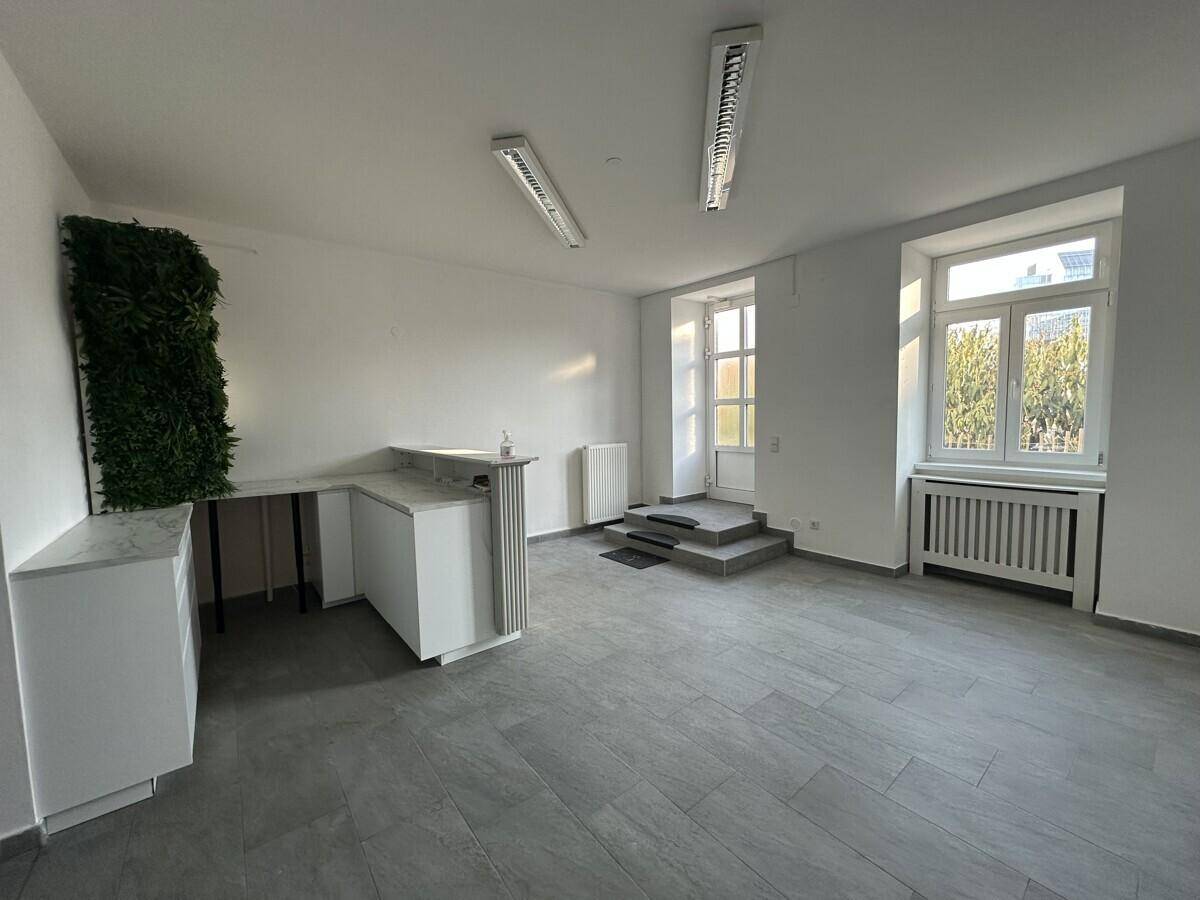 Heller Büroraum mit modernen grauen Fliesen, einer Empfangstheke und einem vertikalen Garten an der Wand.