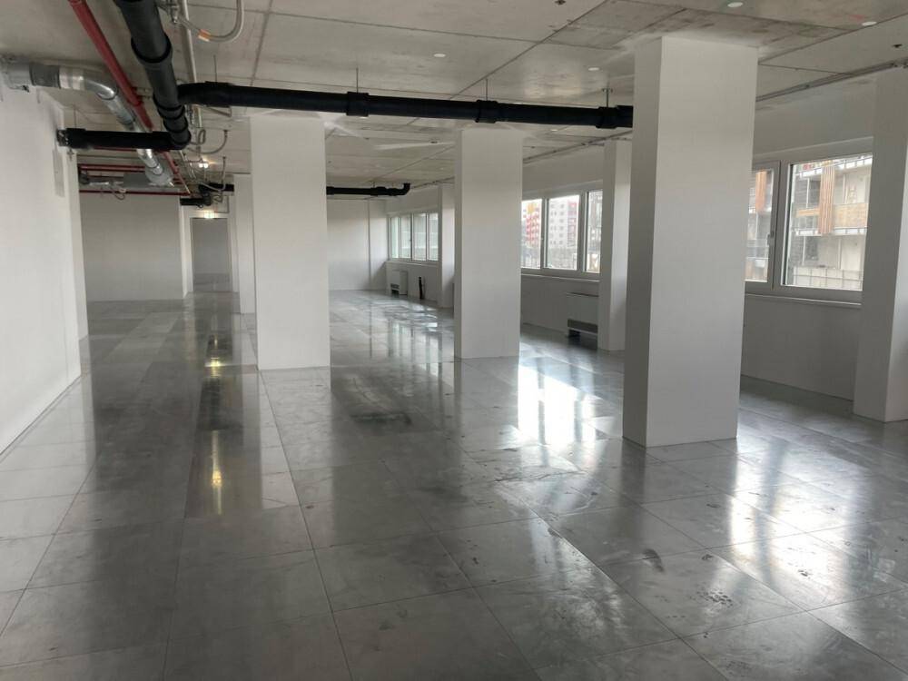 Großer, leerer Gewerberaum mit mehreren Säulen, Fliesenboden und sichtbaren Deckeninstallationen.