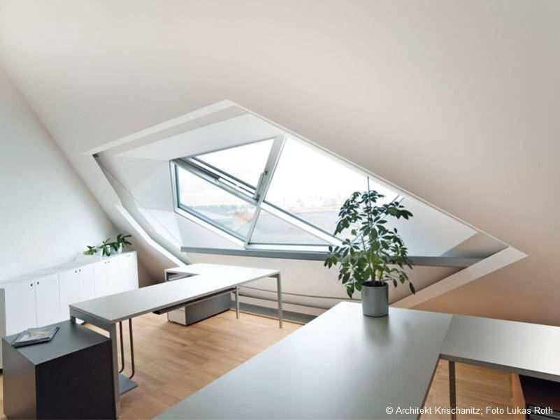 Helles Dachgeschossbüro mit schrägen Wänden, Holzboden und einem großen Dachfenster.