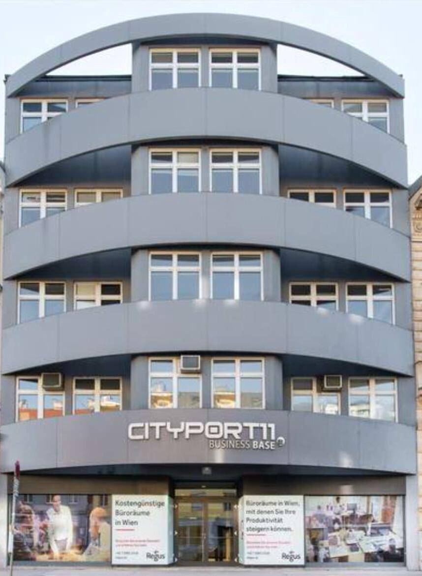 Moderne Bürogebäude-Fassade mit geschwungenen Balkonen und großen Fenstern in Grau und Weiß.