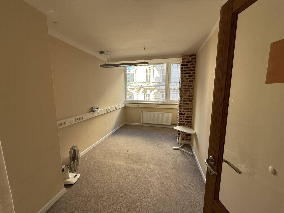 Helles Büro mit Teppichboden, einem Fenster und einer Ziegelwand als dekoratives Element.