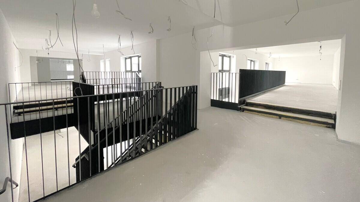 Offener Raum mit Galerieebene, moderner schwarzer Treppe und viel Tageslicht.