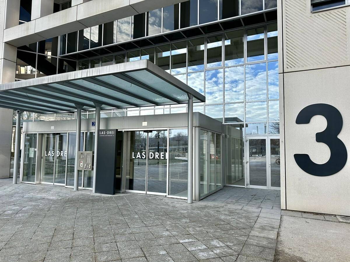 Eingangsbereich eines modernen Bürogebäudes mit Glasfassade und Vordach.