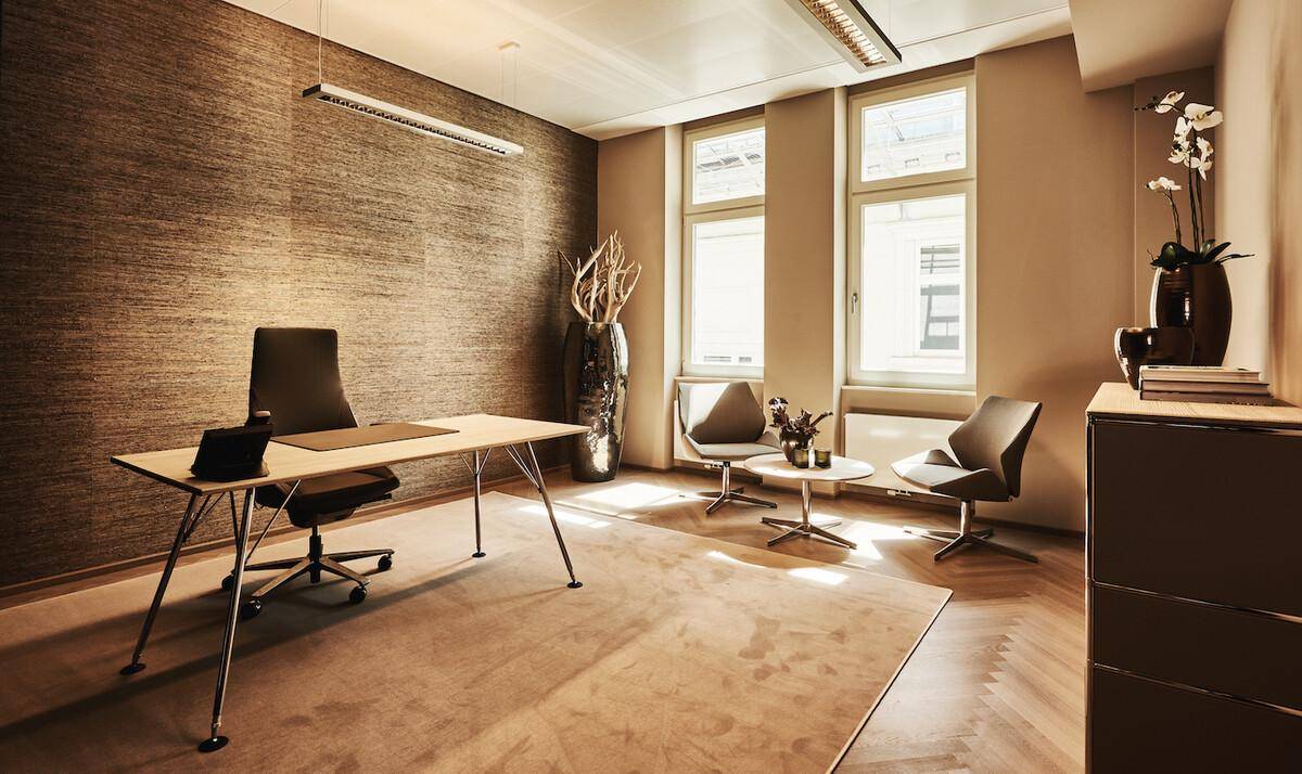 Geräumiges Büro mit modernem Schreibtisch, bequemen Besuchersesseln und strukturierten Tapeten.