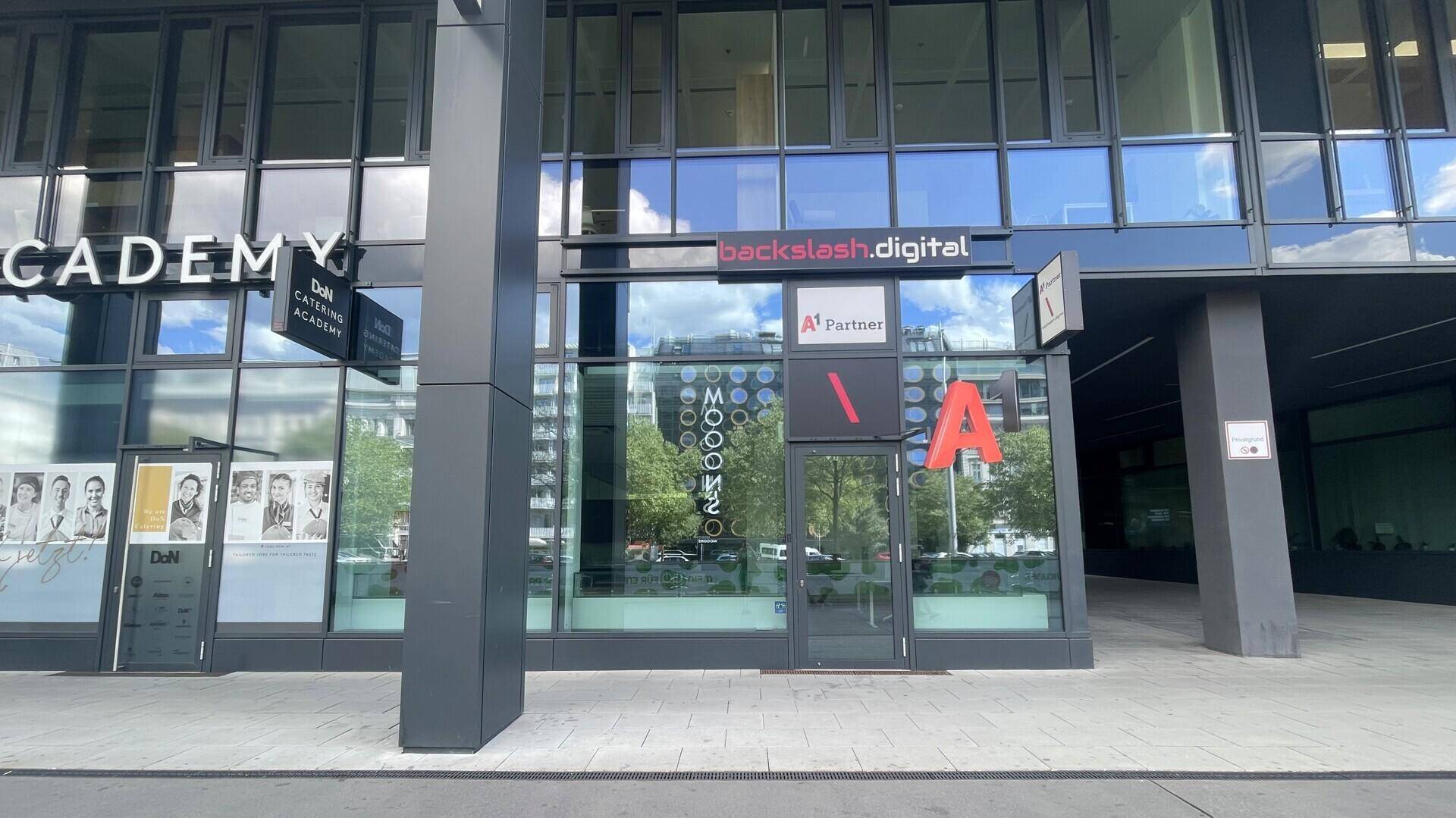 Ansicht der modernen Geschäftsfassade mit großen Fensterfronten und verschiedenen Firmenlogos im Stadtzentrum.