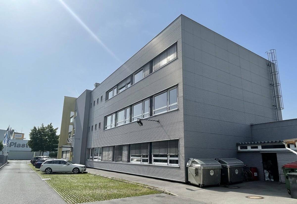 Moderne Bürogebäude-Fassade mit horizontalen Lamellen und zahlreichen Fenstern unter klarem Himmel.