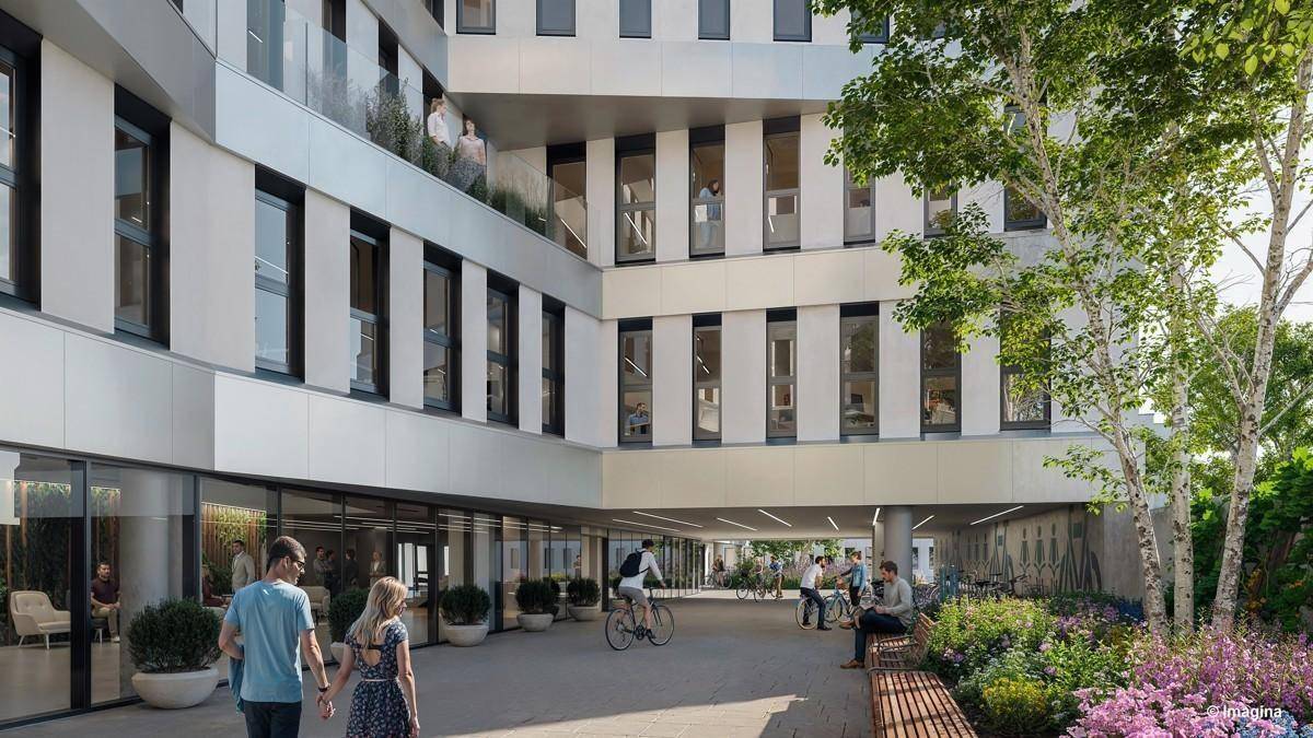 Eingangsbereich eines modernen Bürogebäudes mit begrüntem Innenhof und Sitzgelegenheiten.