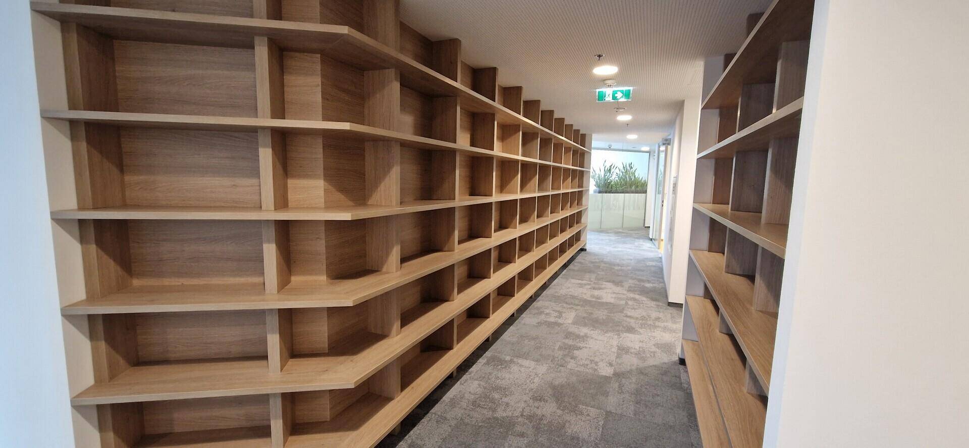 Langer Flur mit durchgehenden, maßgefertigten Holzregalen und Teppichboden.