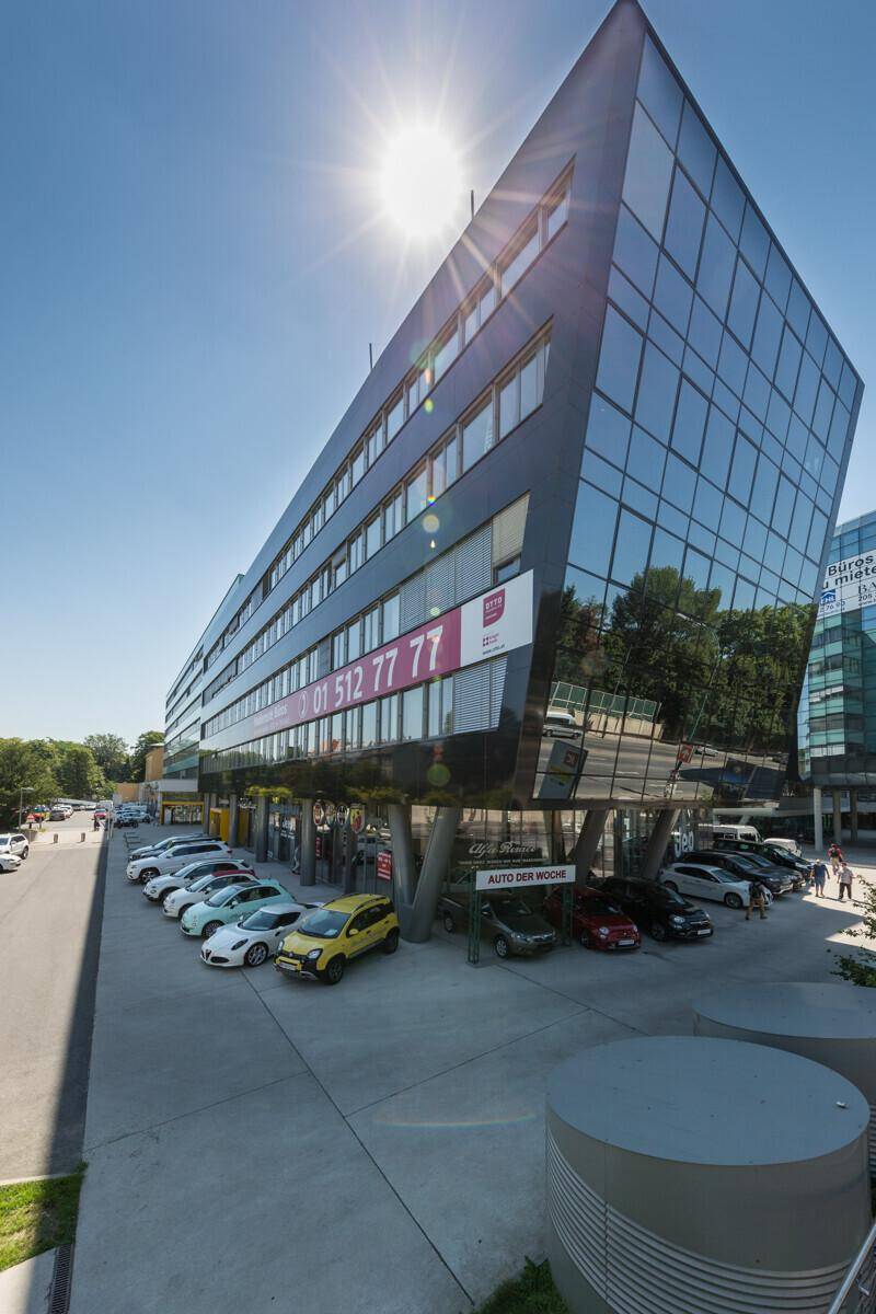 Panoramablick auf das moderne Bürogebäude mit seiner markanten schwarzen und gläsernen Architektur unter strahlendem Sonnenschein.