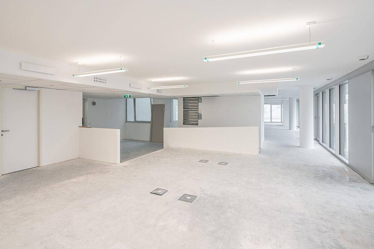 Großer, leerer Büroraum mit weißen Wänden, Betonboden und moderner Beleuchtung, bereit für die individuelle Gestaltung.
