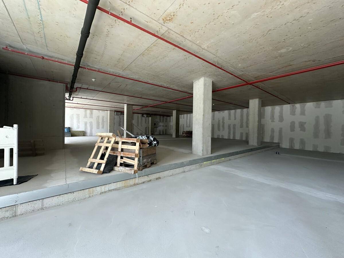 Ein großer, unfertiger Gewerberaum mit Betonboden, Säulen und sichtbaren Leitungen an der Decke.