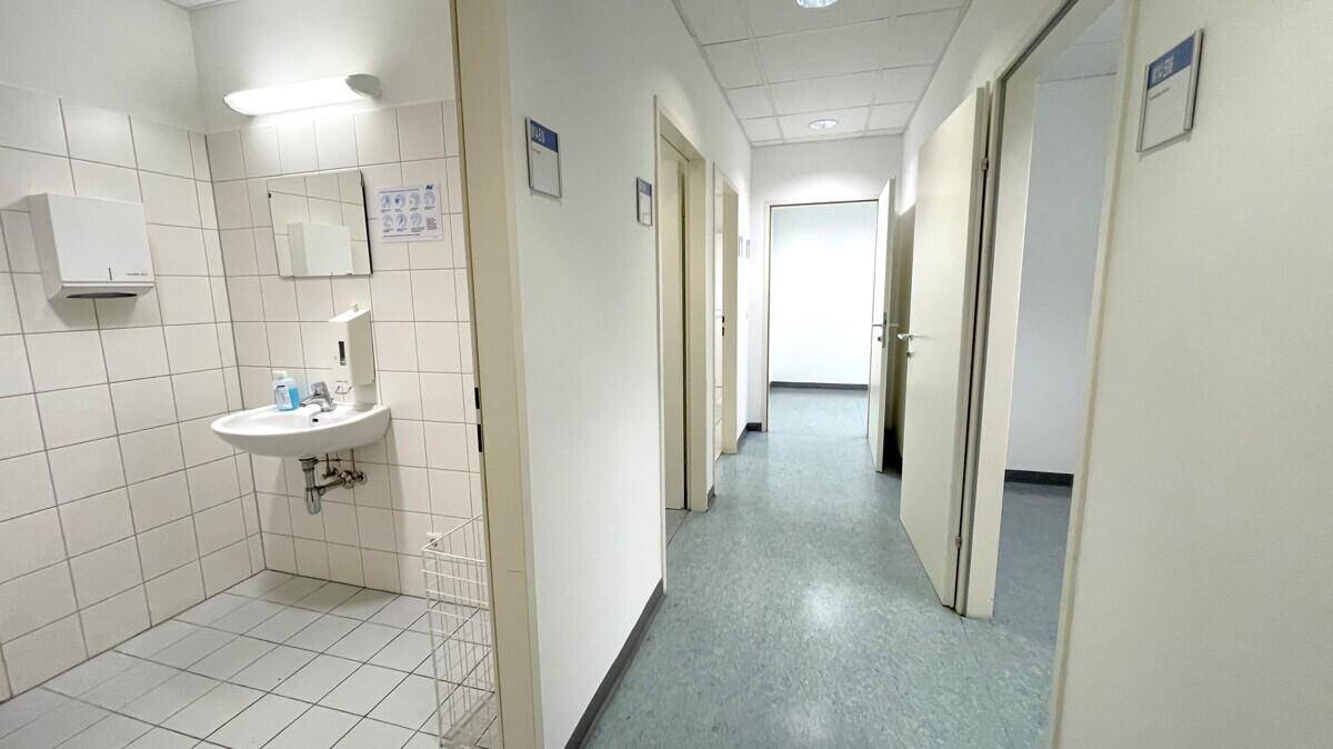 Heller Flur mit mehreren Türen und einem Waschbereich auf der linken Seite.
